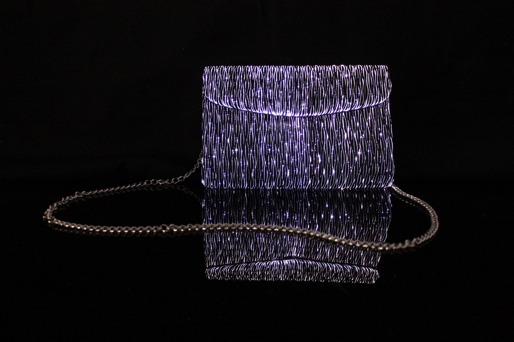 Illuminated evening clutch woven from fiber-optic mesh